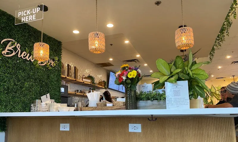 Plant-filled pickup counter inside The Brew Box Coffee Company