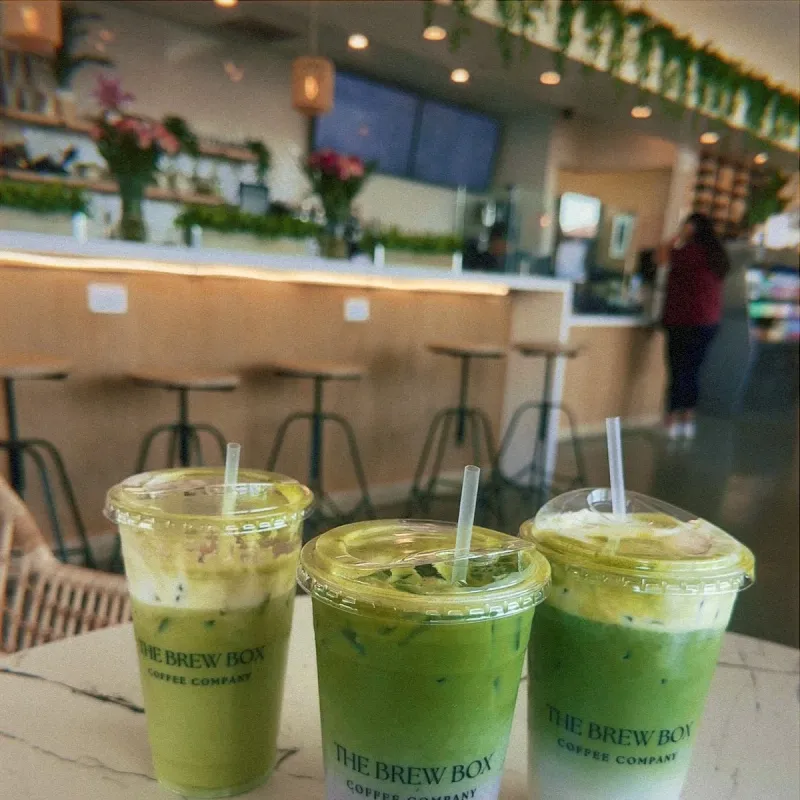 Three matcha drinks on a café table inside Brew Box